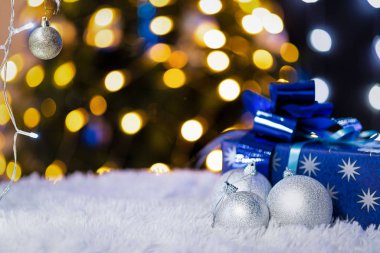Beyaz ekose üzerinde Noel oyuncakları olan yeni yıl kartı. Bokeh içinde fenerler olan soyut mavi arkaplan.