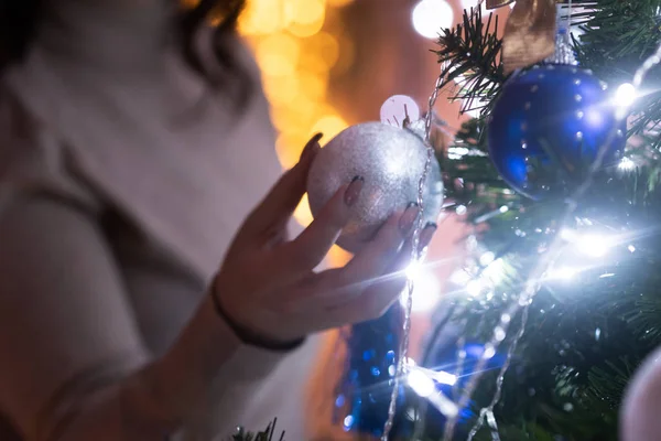 Kadın elinde Noel süsü, Noel ağacında gümüş top tutuyor. — Stok fotoğraf