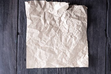 Kırsal tarzda ahşap gri bir masa üzerinde buruşuk bir Kraft kağıdı.