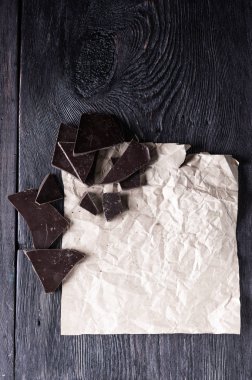 Buruşuk kraft kağıdı ve ahşap bir masanın üzerine kırsal tarzda çikolata parçaları. Mutfak işi konsepti
