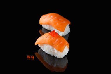 Somonlu sushi nigiri, siyah arka planda kırmızı havyarlı Syake. Bir tabak pirinç ve kırmızı balık.
