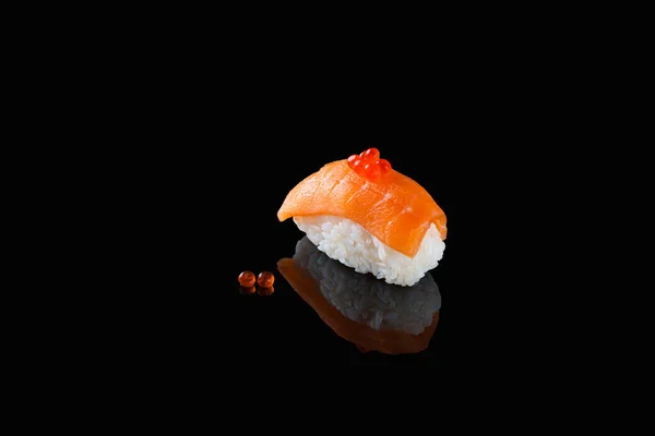 Sushi nigiri with salmon - Syake with red caviar on a black background with reflection. A dish of rice and red fish — Stock Photo, Image