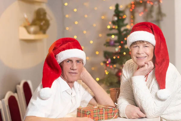 Elderly couple man and woman celebrate Christmas in red santa claus caps — 스톡 사진