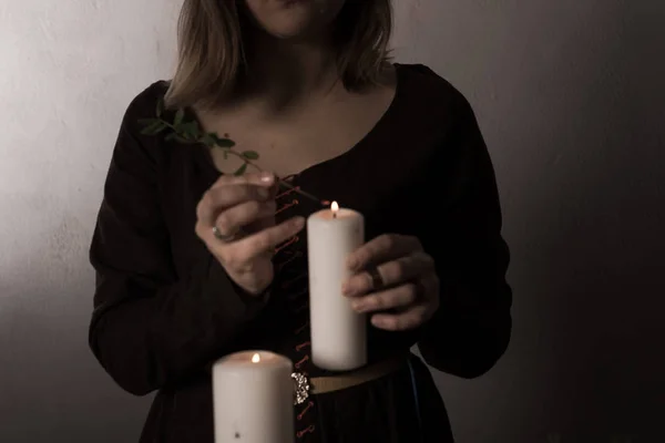 Μια γυναίκα ντυμένη με μεσαιωνικό φόρεμα κρατά ένα αναμμένο λευκό κερί στο χέρι της. Μυστηριώδης μάγισσα — Φωτογραφία Αρχείου