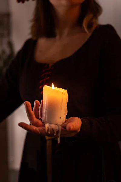 一个穿着中世纪衣服的女人手里拿着一根燃烧着的白色蜡烛。 神秘的巫婆 — 图库照片
