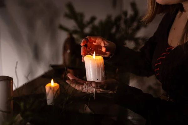 Женщина в средневековом платье держит в руке горящую белую свечу. Таинственная ведьма — стоковое фото