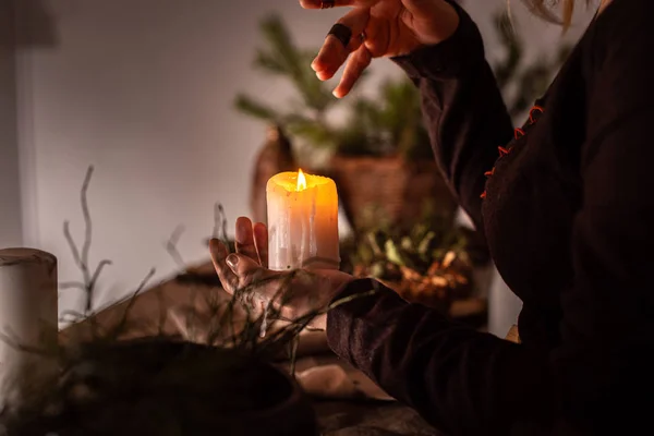 A woman dressed in a medieval dress holds a burning white candle in her hand. Mystery witch — Stock Photo, Image