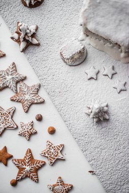 Yıldızlar şeklinde zencefilli kurabiye ve beyaz arka planda kar taneleri. beyaz cila ile boyanmış