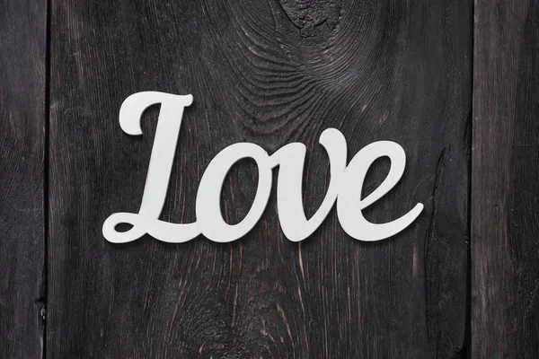 Das Wort Liebe ist ein Holzprodukt auf einem hölzernen grauen Hintergrund, als Begriff der Liebe, ein Symbol. — Stockfoto