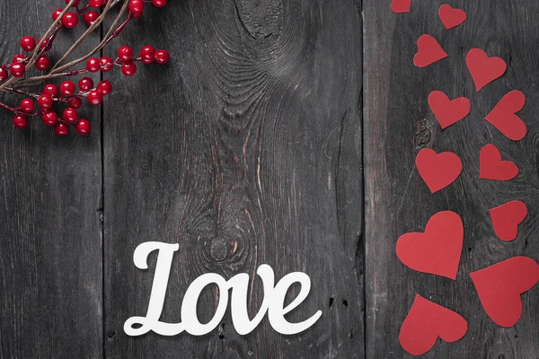 Слово "любовь" на деревенском фоне с красными картонными сердцами сбоку как символ Дня Святого Валентина — стоковое фото