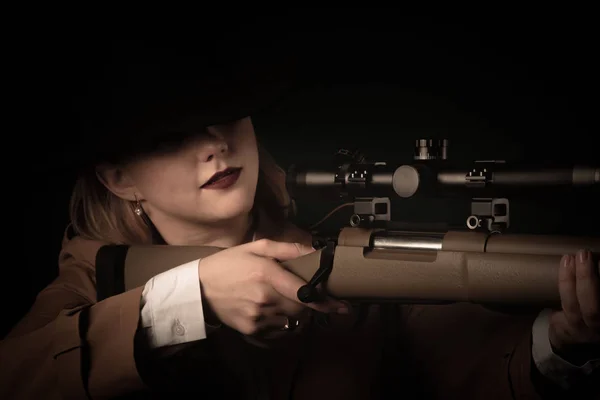 Жінка в коричневому плащі і чорний капелюх з пістолетами в руках дивиться на вигляд. розмитий фокус — стокове фото