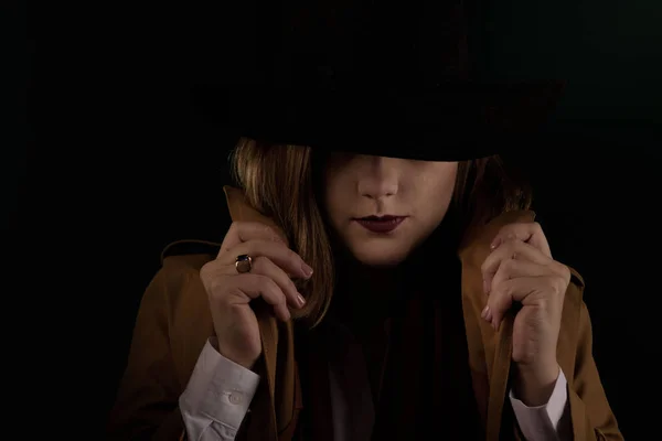 Retro gangster woman in a brown cloak and black hat. Photoshoot in the style of the mafia. Dark blurred background. image focus shift at the top of the frame. — Stock Photo, Image