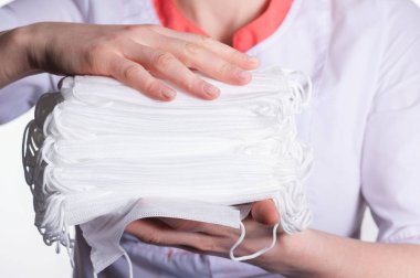 Doktorun elinde bir sürü tıbbi maske var.