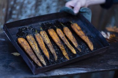 Siyah bir tavada taze havuç yapma süreci.