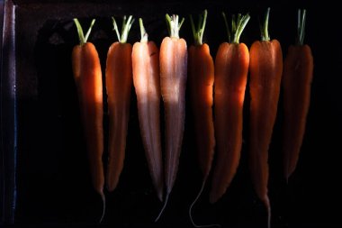 Siyah bir tavada taze havuç yapma süreci.