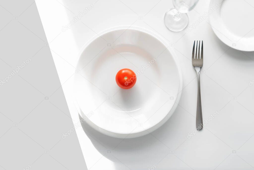 Table setting example. white plates on a white background in the light of the sun. Tomato on a plate. place for text