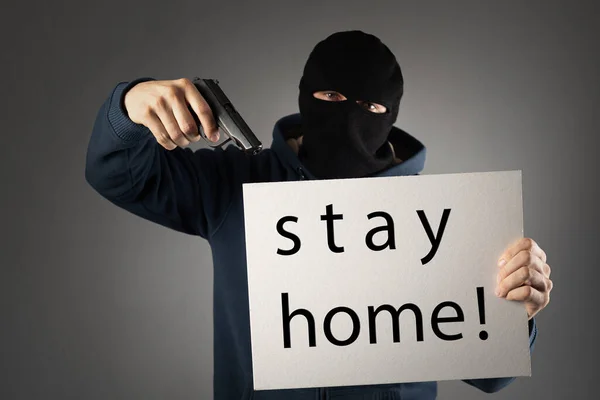 Zostań w domu. uzbrojony mężczyzna w masce na głowie i z pistoletem w rękach — Zdjęcie stockowe