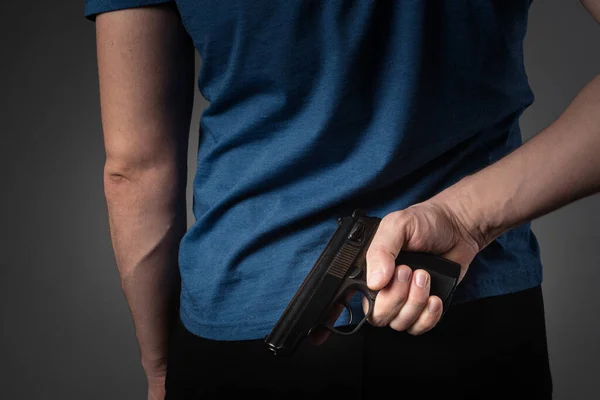 Um homem de t-shirt azul puxa uma arma pelas costas — Fotografia de Stock