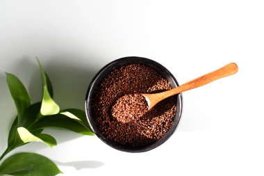 Beyaz bir arka planda kinoa taneciği kırmızısı, siyah bir klozette yatar.