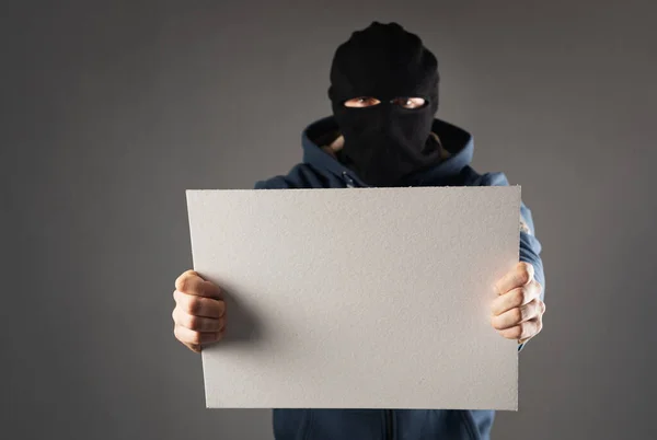 Hombre armado con una máscara en la cabeza y con un arma en las manos sostiene una señal de texto — Foto de Stock