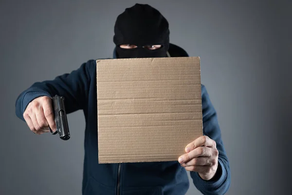 Hombre armado con una máscara en la cabeza y con un arma en las manos sostiene una señal de texto —  Fotos de Stock