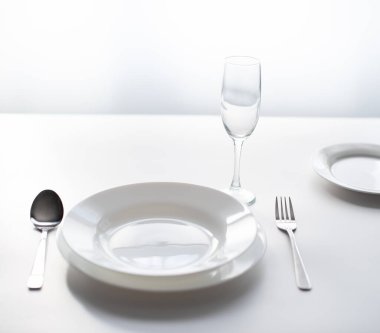 Masanın üzerindeki çatal bıçak takımı, boş bir restoranın penceresinin yanında servis ediliyor. Bir salgın sırasında halka açık alanları ve restoranları kapatma konsepti olarak.