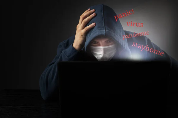 Ord flyger ut ur laptopen - panik, pandemi, virus, stanna hemma. Masked man läsa pandemiska nyheter — Stockfoto