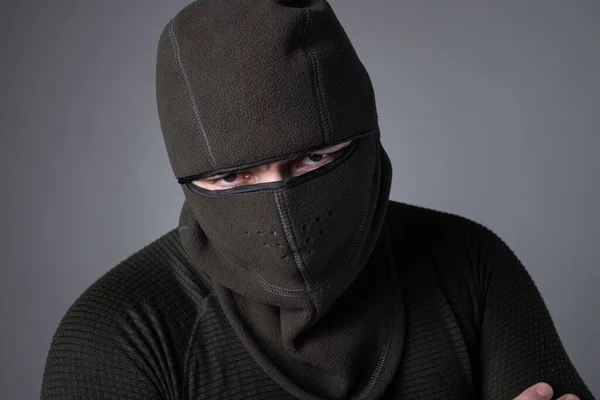 Um homem em uma balaclava, como um conceito de forças especiais ou roupas extremistas, fica com um olhar ameaçador — Fotografia de Stock