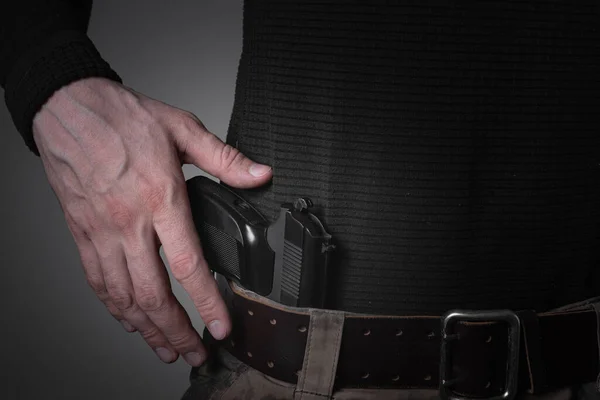 Homem militar ou criminoso puxando uma arma de seu cinto com a mão — Fotografia de Stock