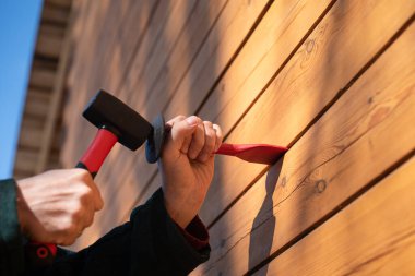 Kerestelerden ahşap bir evi ısıtma işlemi, caulk jute ile. Kazan ve çekiç ellerinde.