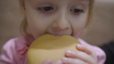 Güzel, mutlu, aç bir kız bebek hamburger yiyor. Fast food ile çocuk sahibi olmak