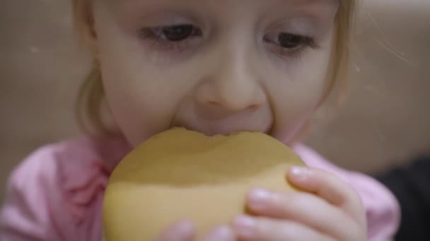 Hermosa niña hambrienta feliz comiendo hamburguesa. Concepto niño con comida rápida — Vídeo de stock