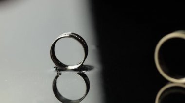 Alyanslar siyah, beyaz su yüzeyinde. Damat yüzüğü gelinlere takılıyor.