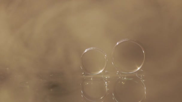 Wedding rings on dark water surface shining with light. Close up macro — Stock Video
