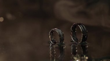 Karanlık su yüzey parlayan ışık ile üzerinde alyans. Makroyu kapat