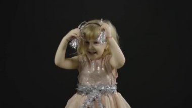 Parlak elbiseli mutlu küçük kız bebek. Noel zamanı. Yüz yap, dans et.