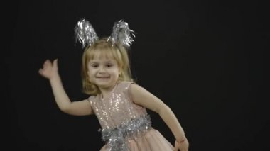 Parlak elbiseli mutlu küçük kız bebek. Noel zamanı. Yüz yap, dans et.