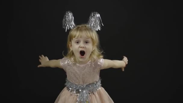 Parlak elbiseli mutlu küçük kız bebek. Noel zamanı. Yüz yap, dans et. — Stok video