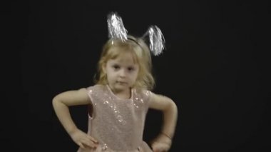 Parlak elbiseli mutlu küçük kız bebek. Noel zamanı. Yüz yap, dans et.