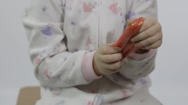 Малюк грає з ручним іграшковим слизом. Дитина весело робить рожевий слиз — стокове відео