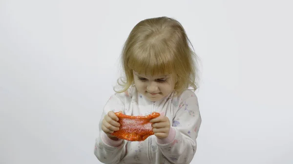 Dzieciak bawi się ręcznie robionym śluzem zabawek. Dziecko dobrze się bawiące robiąc pomarańczowy szlam — Zdjęcie stockowe