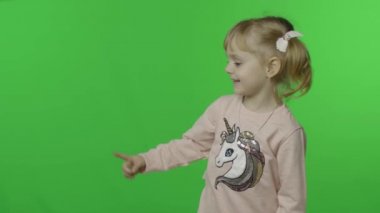 Tek boynuzlu at tişörtlü kız duygusal olarak elleriyle bir şeyi işaret ediyor.