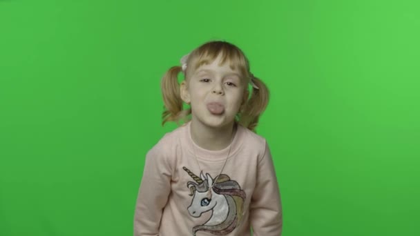 Az egyszarvú pulcsis lány megmutatja a nyelvét és a mosolyát. Boldog gyerek. Kroma kulcs — Stock videók