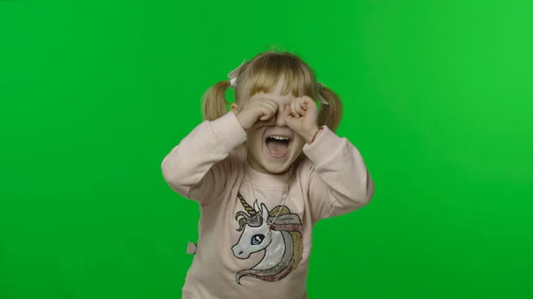 Dívka v mikině s jednorožcem dělá obličeje a pláče. Šťastné dítě. Klíč Chroma — Stock fotografie