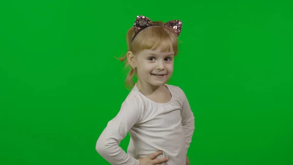 Chica en diadema de gato mira a la cámara y sonríe. Feliz niño de cuatro años — Foto de Stock