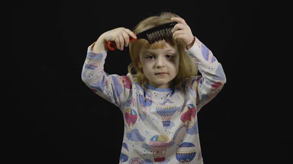 Petite fille en pyjama avec coiffure drôle peigne. Fond noir — Photo