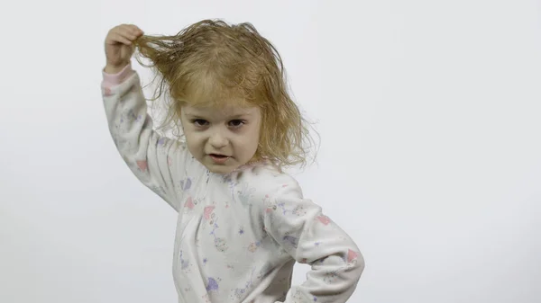 Het kleine meisje in pyjama loopt rond en trekt gezichten. Witte achtergrond — Stockfoto