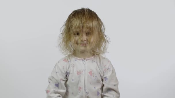 La niñita en pijama está tonteando y haciendo caras. Fondo blanco — Vídeo de stock