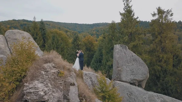 A friss házasok a hegy magas lejtőjén állnak. Vőlegény és menyasszony. Légi felvétel — Stock Fotó