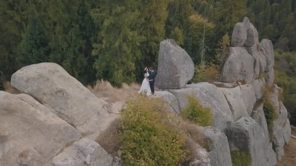 Pasgetrouwden staan op een hoge helling van de berg. Bruidegom en bruid. Luchtzicht — Stockvideo